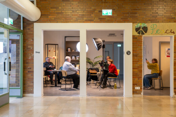 Im Zeitzeugeninterview berichtet der ehemalige Pfarrer im Notaufnahmelager Gießen, Matthias Leschhorn, der GEDG-Mitarbeiterin Margarete Puhl (GEDG) und Johannes Romeyke (musealis) von seinen Erfahrungen. Dahinter dokumentiert Leona Ludwig (GEDG) für die Öffentlichkeitsarbeit, 5. Dezember 2025 (Christian Faludi/GEDG)