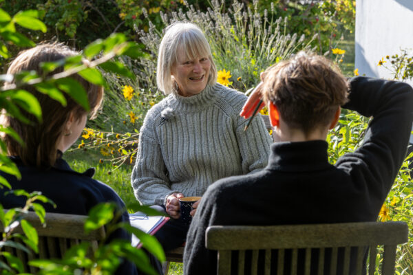 Sabine Reichwein berichtet im Garten ihres Hexenhauses in Vitte auf Hiddensee von ihren Erinnerungen an die Umbruchszeit, Lena-Marie Forkel und Margarete Puhl führen das Interview, 21. September 2025 (Christian Faludi/GEDG)