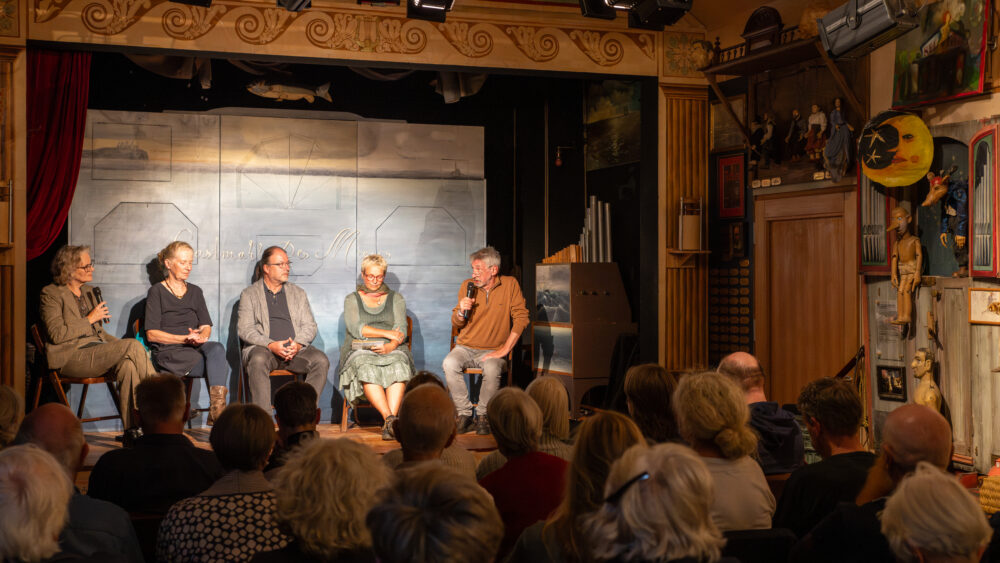 Auf der Bühne des Figurentheaters Homunkulus diskutieren (von rechts): Hasso Spode, Marion Magas, Burkhard Bley und Christiane Wolff, Liane von Billerbeck moderiert das Gespräch, 21. September 2025 (Christian Faludi/GEDG)